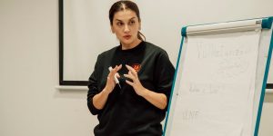 Woman confidently presenting with a flip chart in a classroom setting.